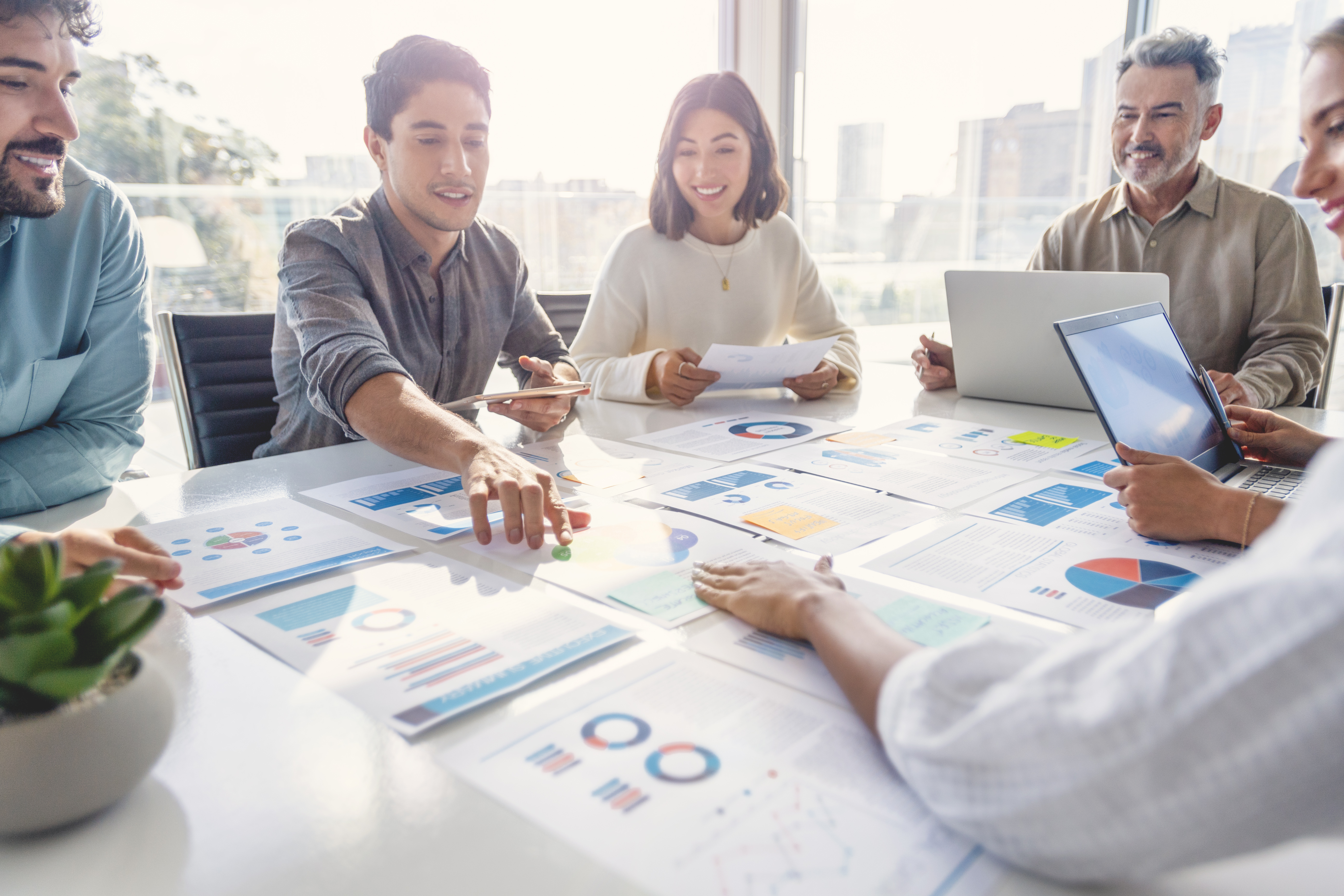 A diverse group of people working with paperwork on a board room table