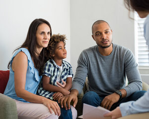 3 family members sat on a sofa, talking to a counselor
