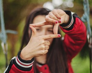 young woman in red making square frame with fingers
