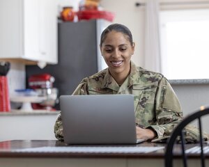 Air Force Service Member at home writing on laptop