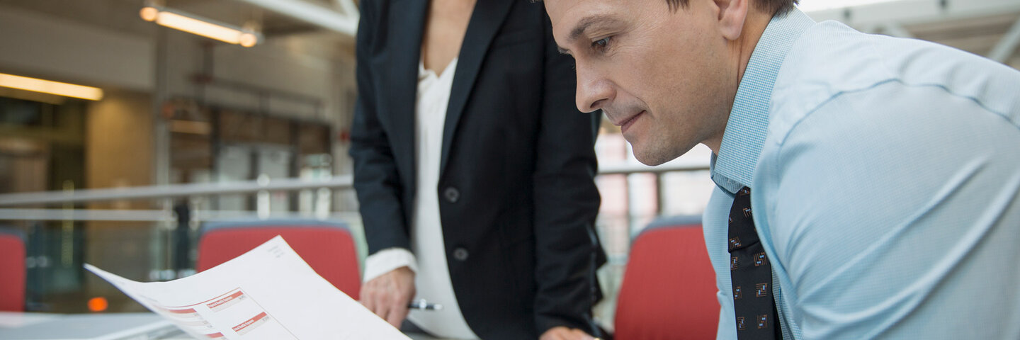 A businessman and woman looking over contracts in warehouse.