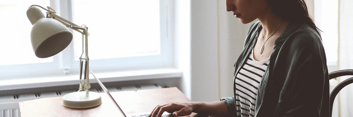 Woman writing on laptop at home desk