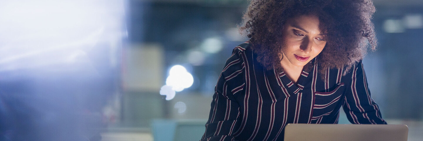 Woman writing at a computer, standing in dramatic light