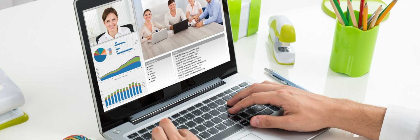 Close-up Of Businessperson Videoconferencing With Colleagues On Laptop In Office