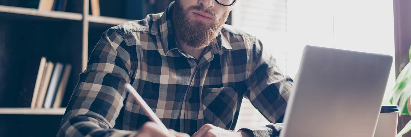 man with laptop and notebook writing