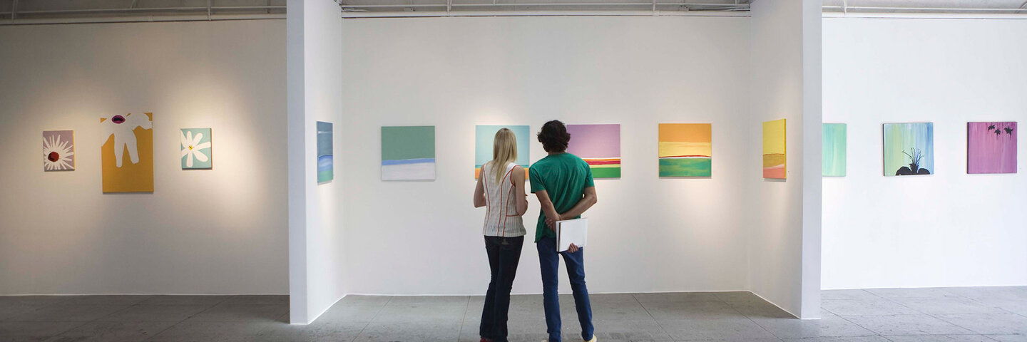 woman and man with notebook looking at art in a gallery