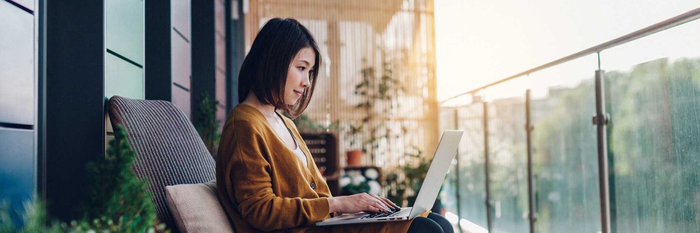 Young woman working on laptop on a balcony