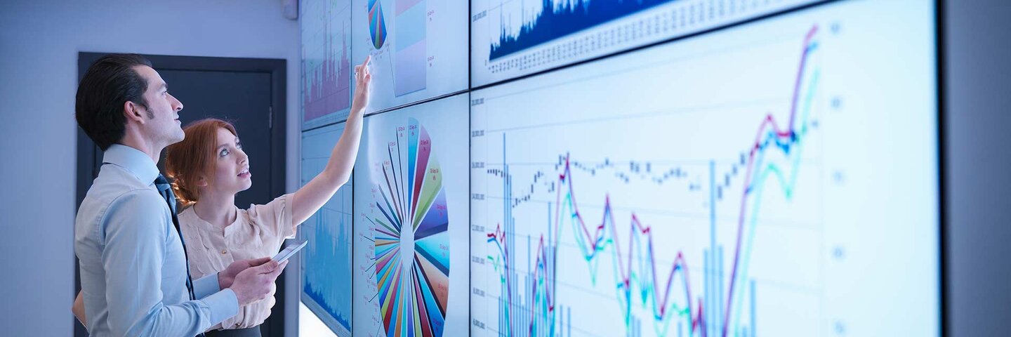 Business colleagues studying graphs on screen in meeting room