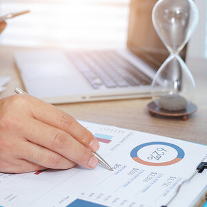 hand holding a pen, writing on a financial document