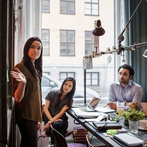 Creative businesswoman giving presentation to colleagues in modern office