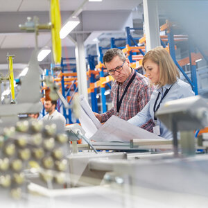 man and woman in factory looking at plans